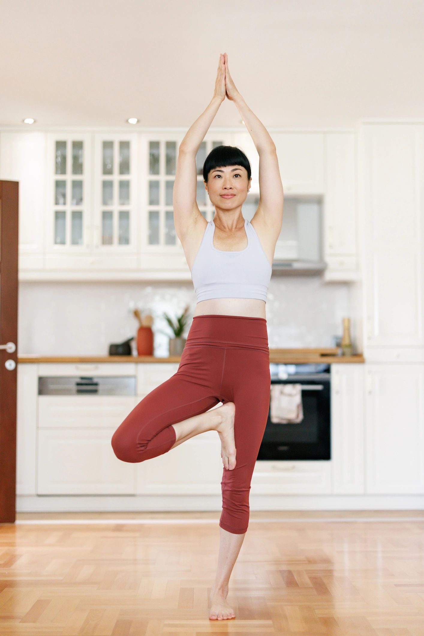 Woman practicing yoga tree pose at home